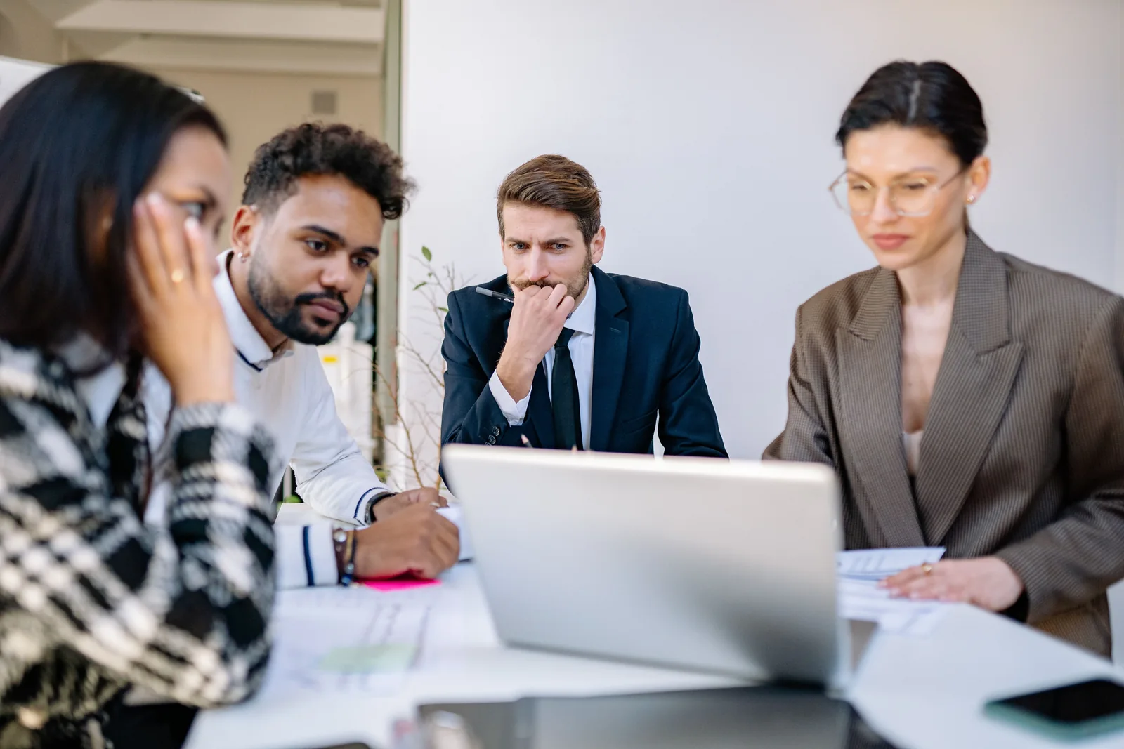 Vier Personen besprechen gemeinsam Inhalte auf einem Laptop im Büro